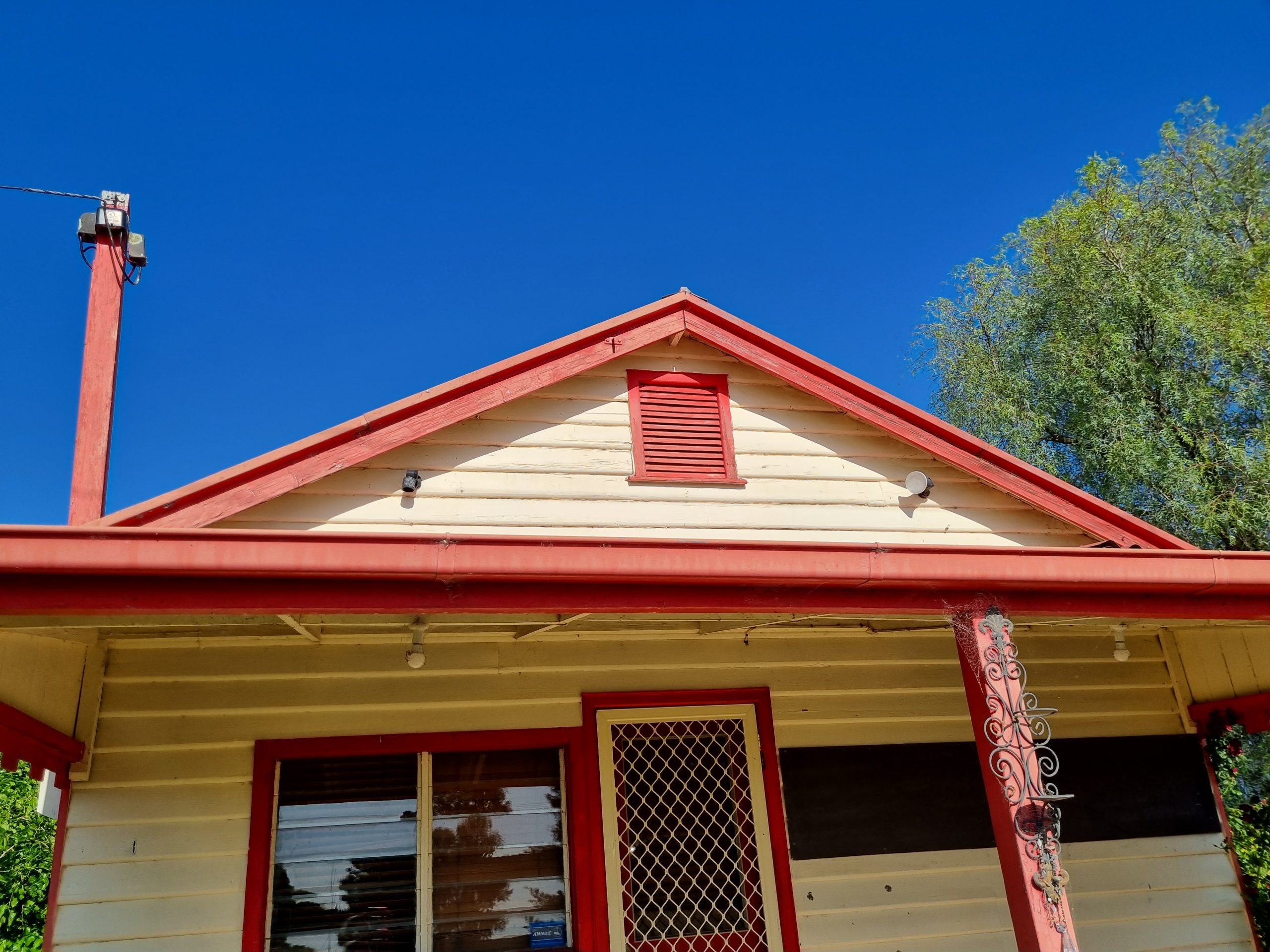 front of house with red veranda poles, guttering and roofline.